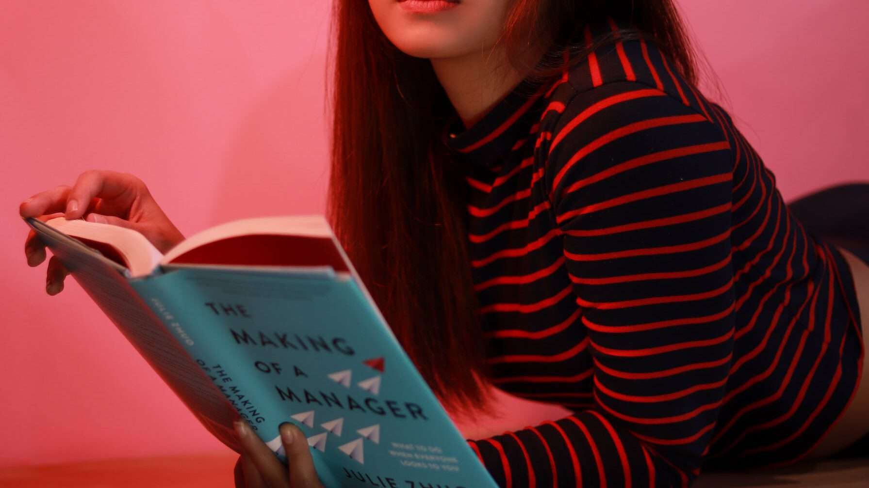 woman in striped long sleeve shirt holding a book